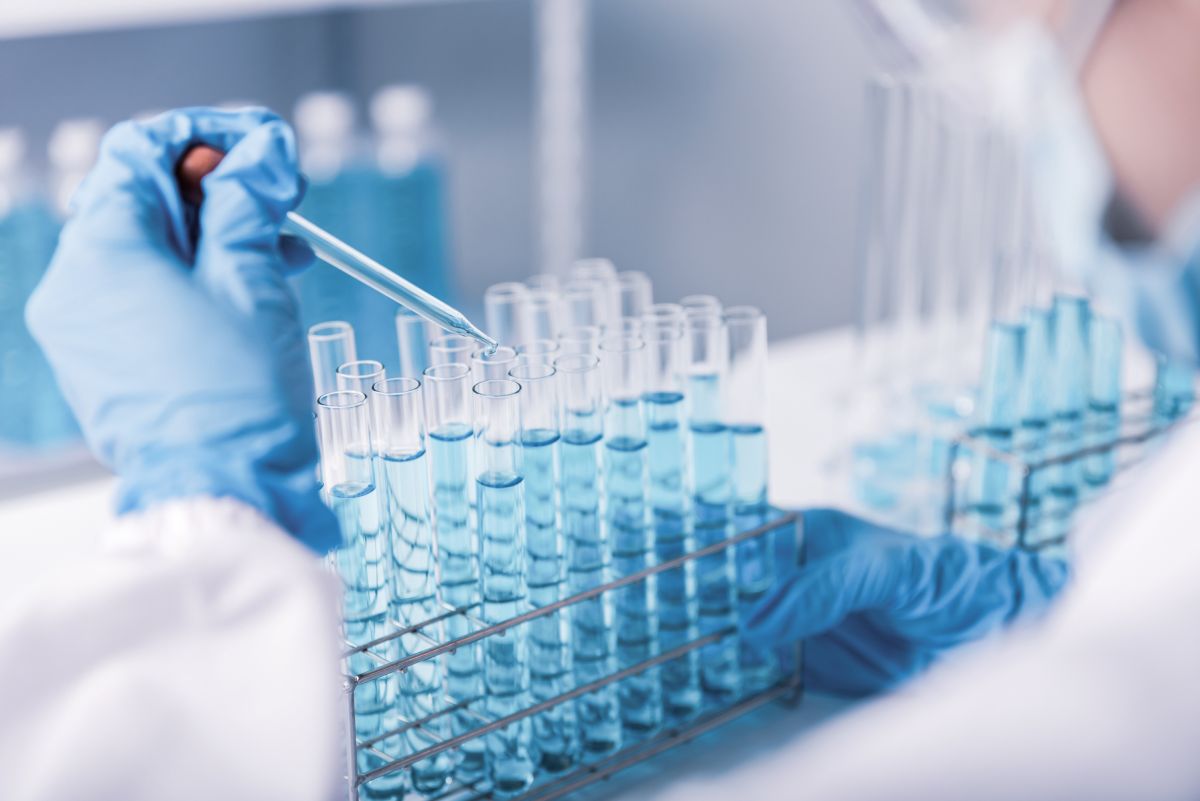 Research scientist dropping chemical into test tubes